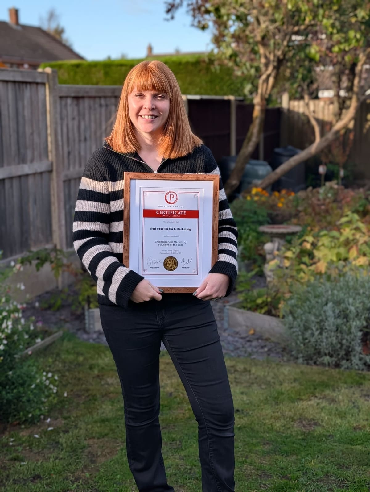 Penny Gibbs holding a Prestige Awards certificate for Red Rose Media & Marketing